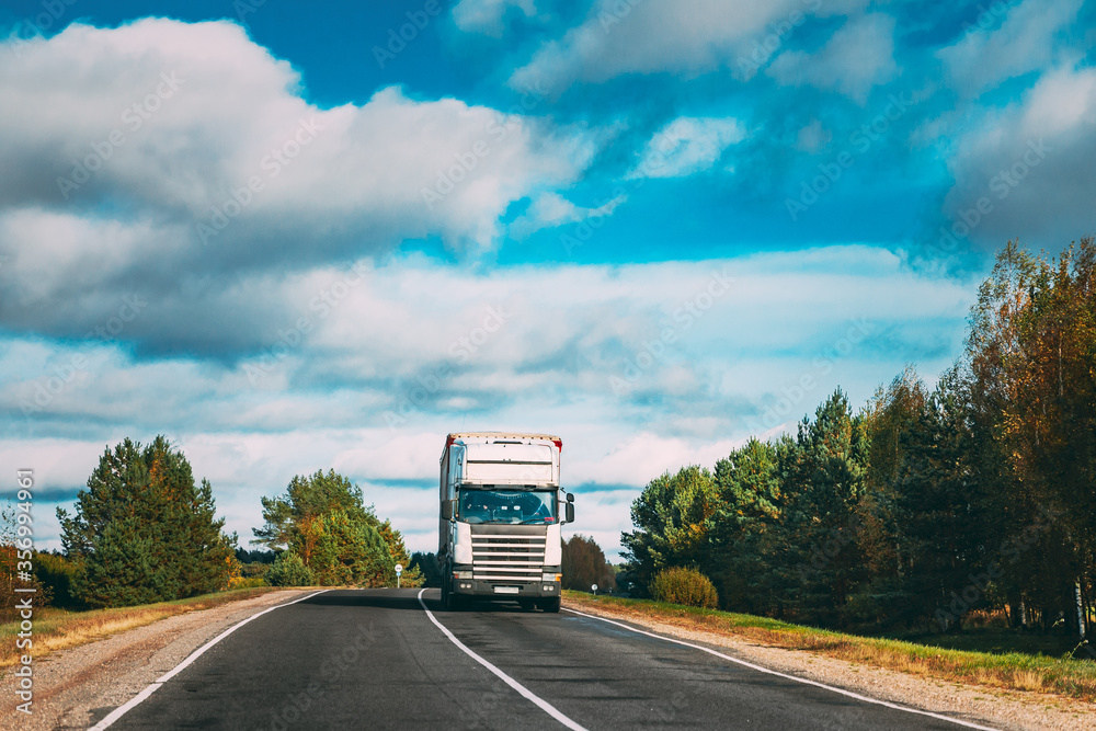White Truck Or Tractor Unit, Prime Mover, Traction Unit In Motion On Summer Road, Freeway. Asphalt Motorway Highway During Sunny Day. Business Transportation And Trucking Industry Concept.