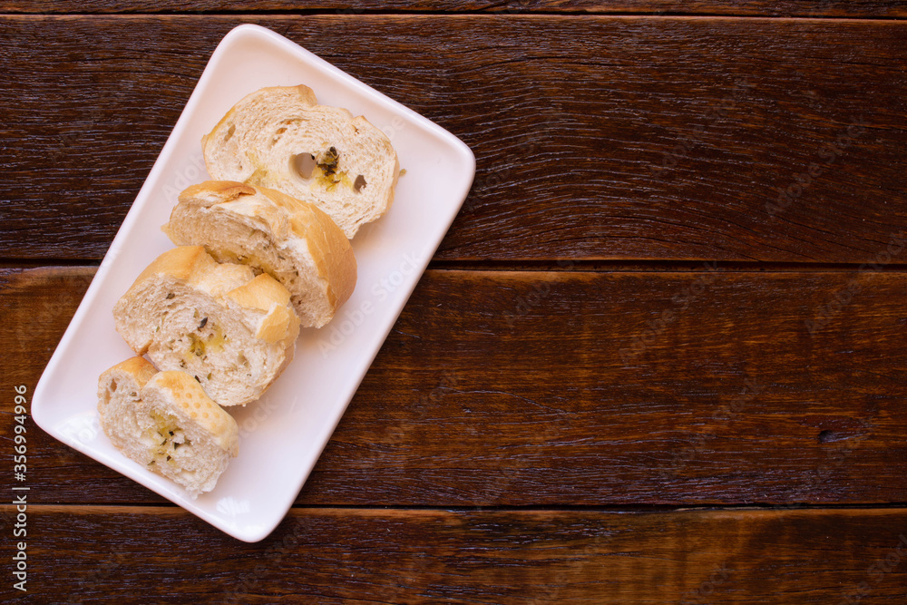 White dish with toasted bread on wooden background. Top view with copy space. White dish with toasted bread on wooden background. Top view with copy space.