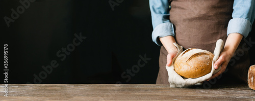 Woman holds in her hands a loaf of freshly sliced bread rustic background. The concept of home-made diet baking without