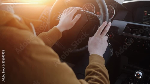 a young man goes behind the wheel at sunset