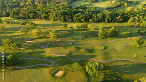 Aerial view of Golf course. Establishing shot, drone flying over golf club. Early morning, summertime, sunlight