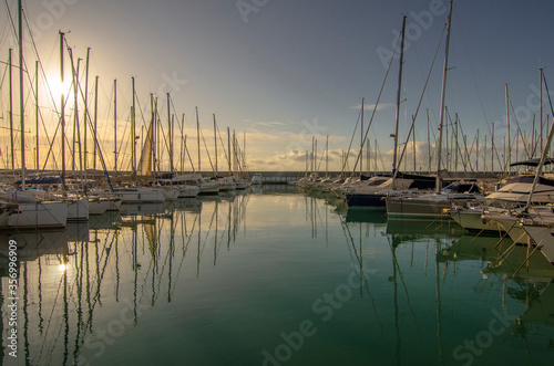 Small port with boats and reflections at sunset © giadophoto