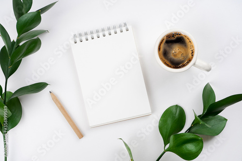 Notebook, coffee, pencil, plant branches on turquoise background. Workspace concept. Top view, copy space, mockup, flat lay