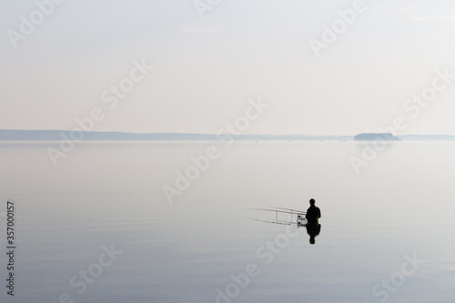 Lonely fisherman on the lake in the morning light