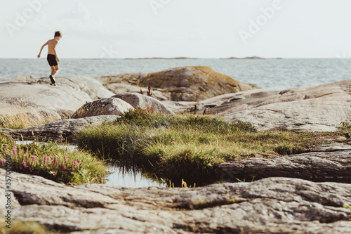 Shirtless boy walking on archipelago during sunny day photo