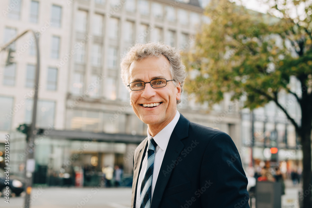 Portrait of smiling businessman wearing suit while standing in city Portrait of smiling businessman wearing suit while standing in city
