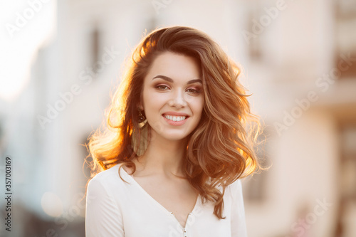 Free Download Portrait of young and beautiful brunette woman emotionally smiling, walking at street,posing, looking away. Girl in hat, with big earrings with perfect make up and wavy hairstyle. Street fashion look. - GFXLoad