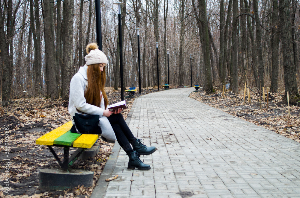 The girl is walking in the park. Read a book.