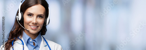 Medical call center service. Online helping and consultation. Female doctor in headset, standing over blurred office background, with copy space empty place for some sign text. photo