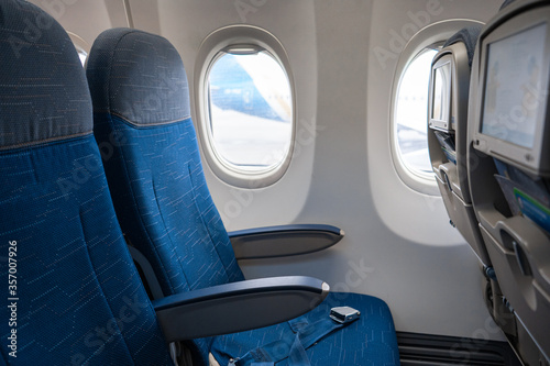 The interior of the aircraft. Empty airplane cabin. Rows of passenger seats with screens in the head restraints