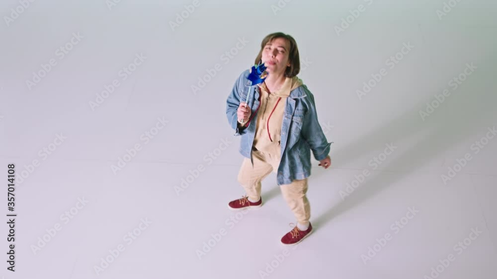 Happy dancing lady with a wind spinner with a short hair in front of the camera in a white background studio Happy dancing lady with a wind spinner with a short hair in front of the camera in a white background studio