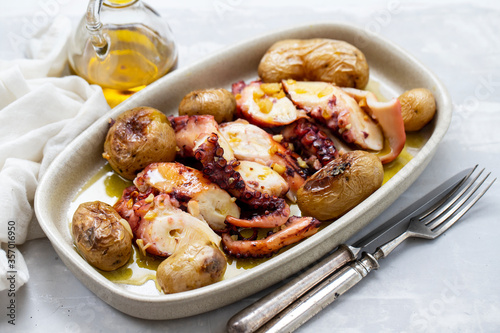 grilled octopus with potato, olive oil on white dish on ceramic background photo