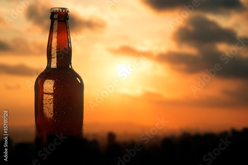 Beer bottle over a bokeh red sky background.
