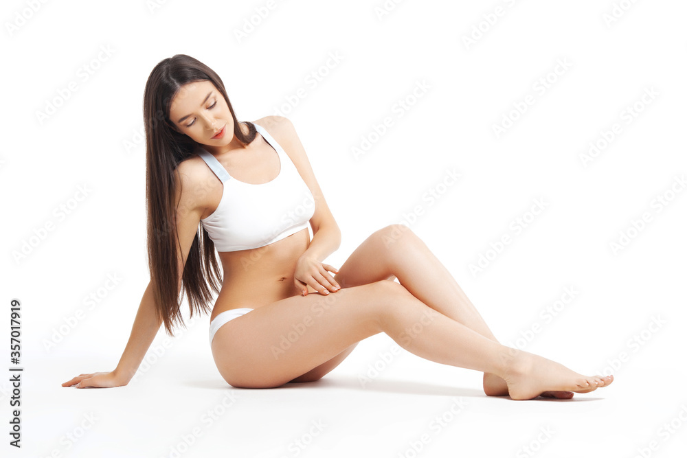 Slim young woman sits in underwear on white background