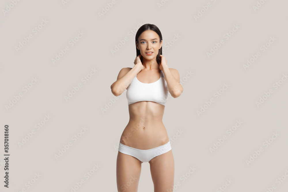 Obraz premium Slim young woman in white underwear on beige background