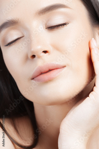 Young beautiful woman with closed eyes does self-massage of face
