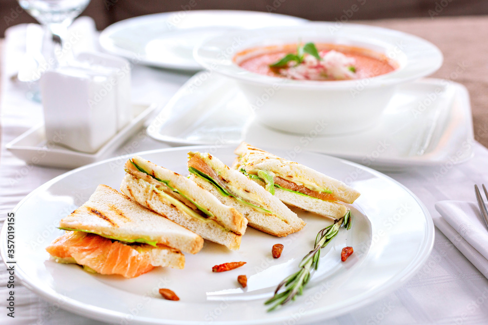Sandwiches with salmon on a white plate. Serving in a restaurant. Sandwiches with salmon on a white plate. Serving in a restaurant.