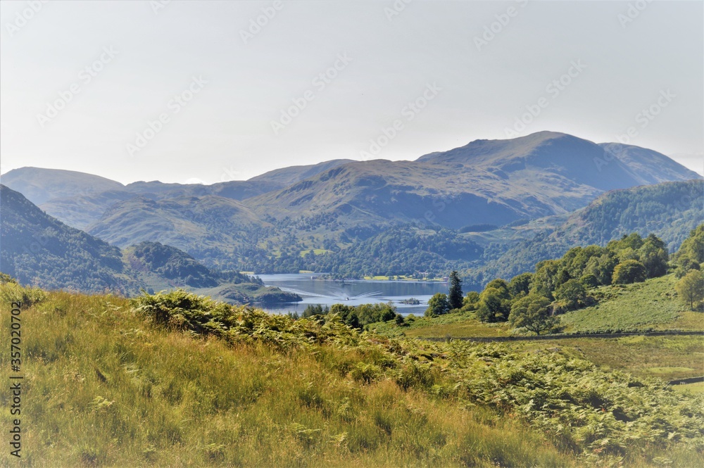 mountain landscape in the Lake District mountains with lake and speedboat in the distance 