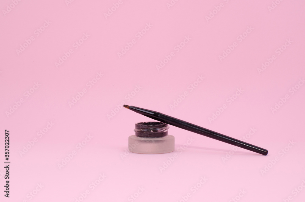 eyeliner pot and her brush. Pink background. eyeliner pot and her brush. Pink background.