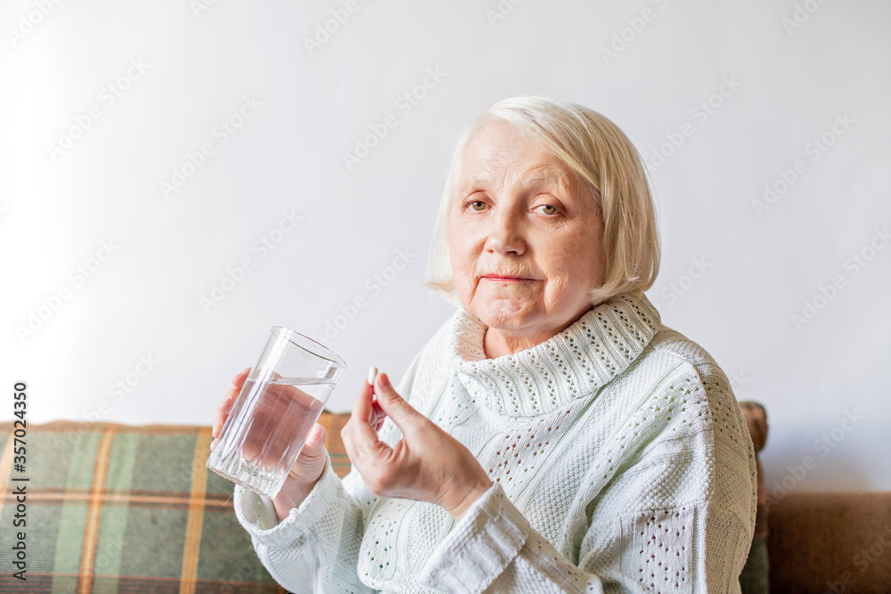 gray-haired elderly senior holding a tablet and a glass of water gray-haired elderly senior holding a tablet and a glass of water