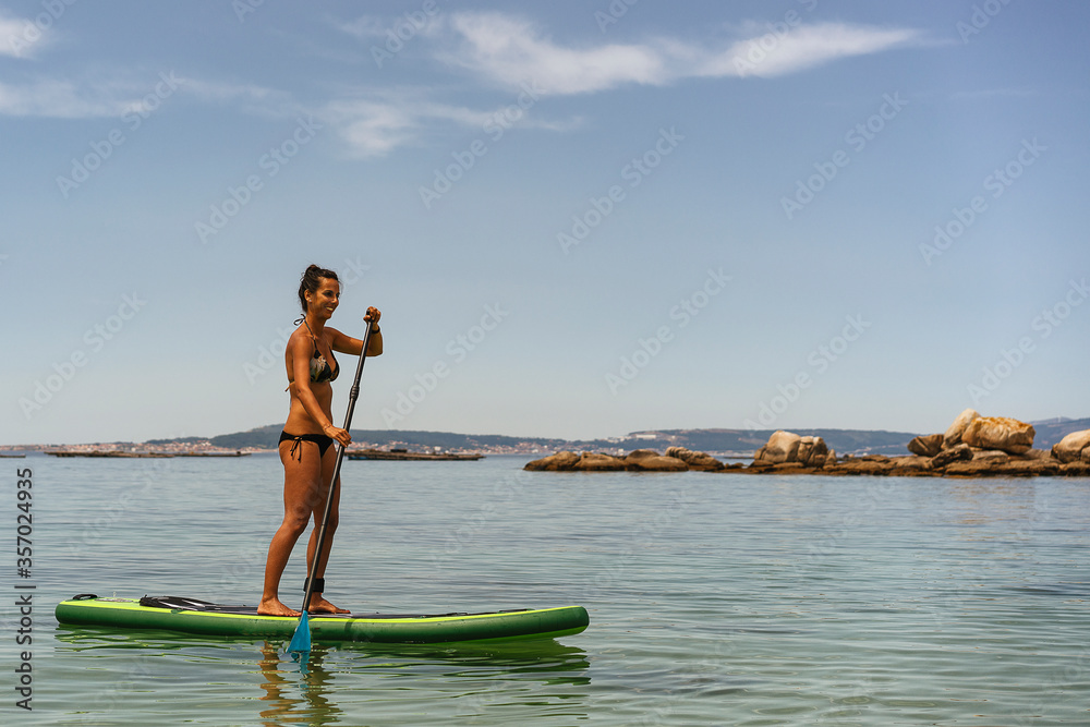Youth woman surfing a paddle board in the ocean