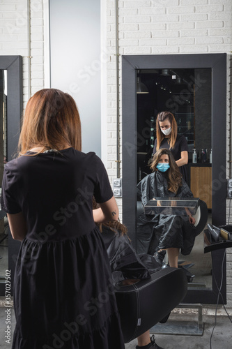 Mujer estilista corta el pelo a mujer clienta, con la mascarilla puesta de protección ante el virus COVID19 photo