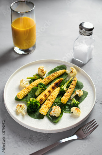 grilled vegetables and juice on a light stone background, dietary vegetarian snack babycorn, healthy low-calorie food, vertical frame
