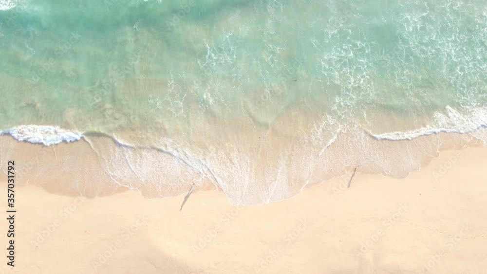 Aerial view top view Beautiful topical beach with white sand. Top view empty and clean beach. Waves crashing beach from above. With people walk and relax on the beach.