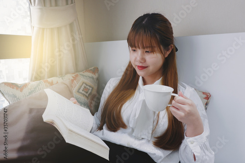 Woman reading a book while drinking a cup of hot coffee.