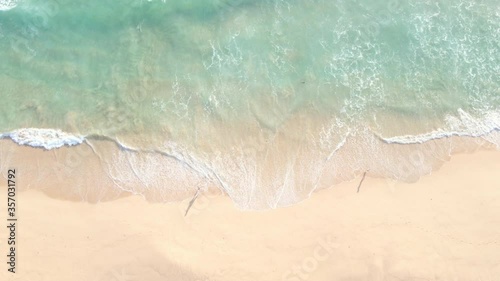 Aerial view top view Beautiful topical beach with white sand. Top view empty and clean beach. Waves crashing beach from above. With people walk and relax on the beach.