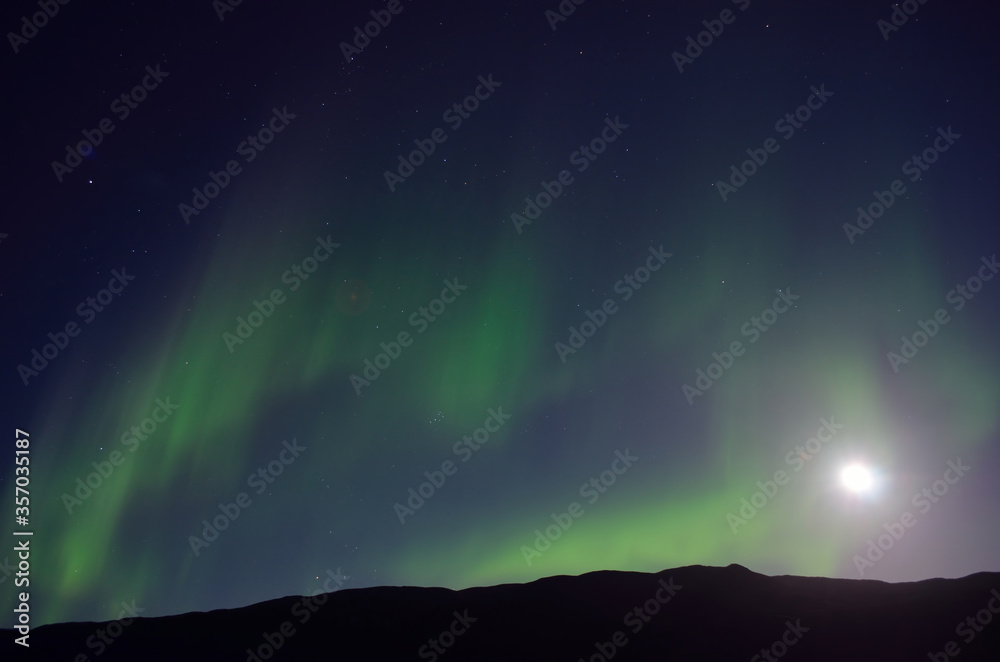 aurora borealis and full moon together over mountain in autumn night