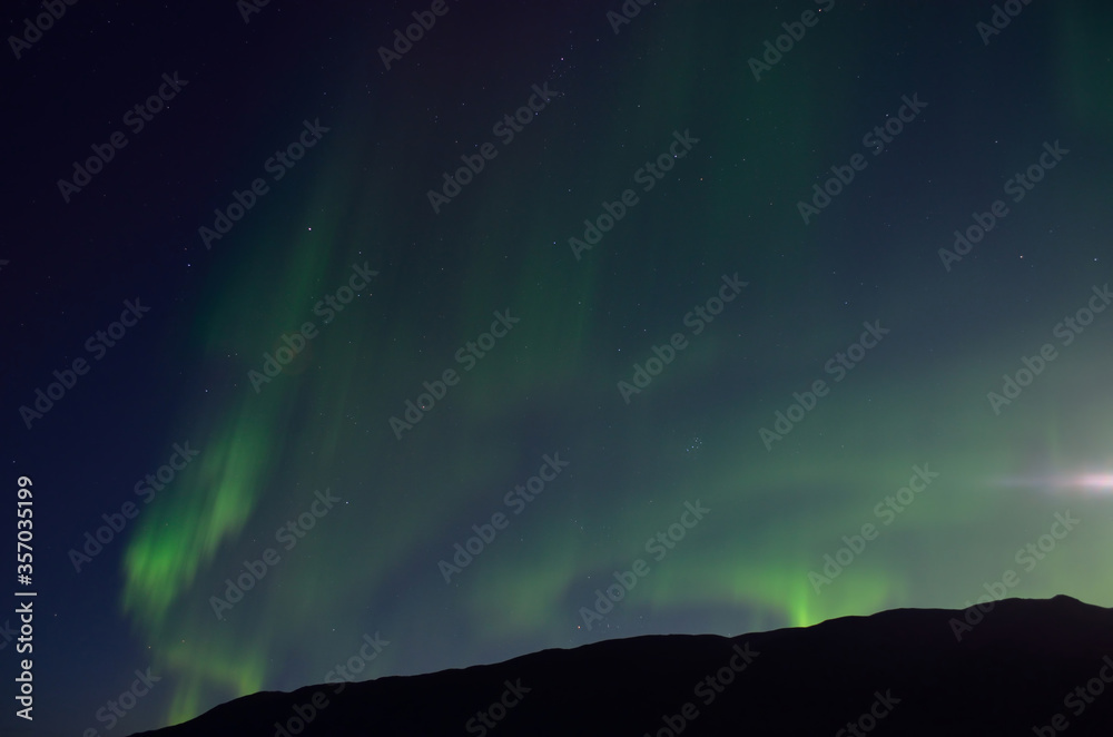 massive aurora borealis dancing on night sky over mountain in northern Norway