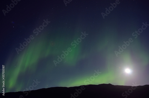 aurora borealis and full moon together over mountain in autumn night © Arcticphotoworks