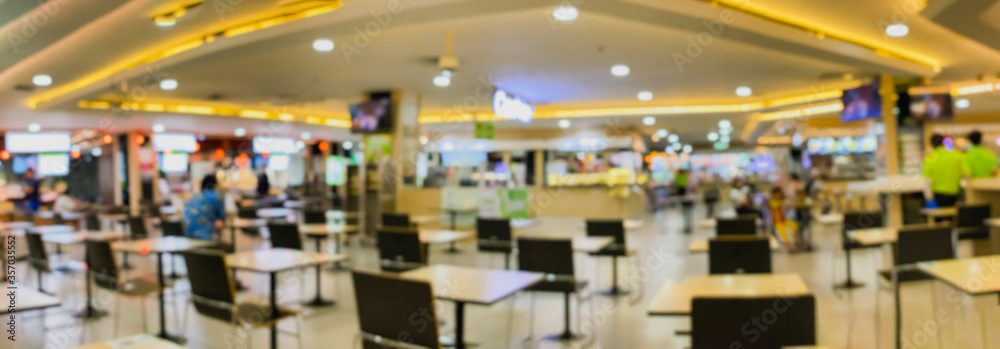 Defocused restaurant in shopping mall with social distancing table pattern