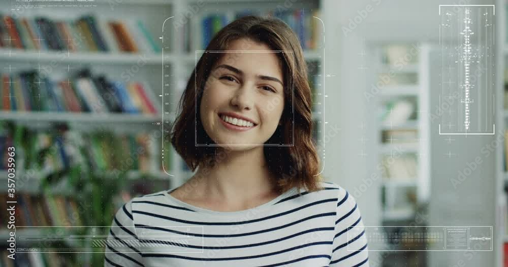 Portrait of young pretty Caucasian girl in library with face recognition technology on. Augmented reality. Biometric facial recognition. Close up of female smilingh to camera. 3D scanning. Portrait of young pretty Caucasian girl in library with face recognition technology on. Augmented reality. Biometric facial recognition. Close up of female smilingh to camera. 3D scanning.