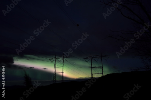beautiful colorful aurora borealis dancing on night sky over massive power grid structure