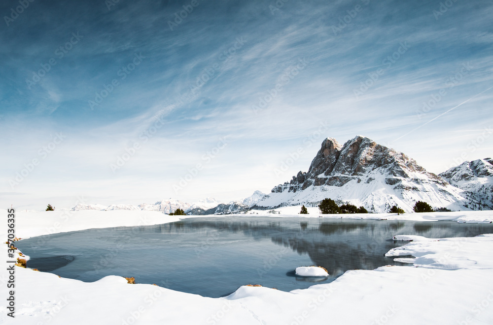 Awesome view on a winter landscape with snow, a lake in the foreground and an amazing rocky mountain in the background. Alps, Dolomites, Peitlerkofel