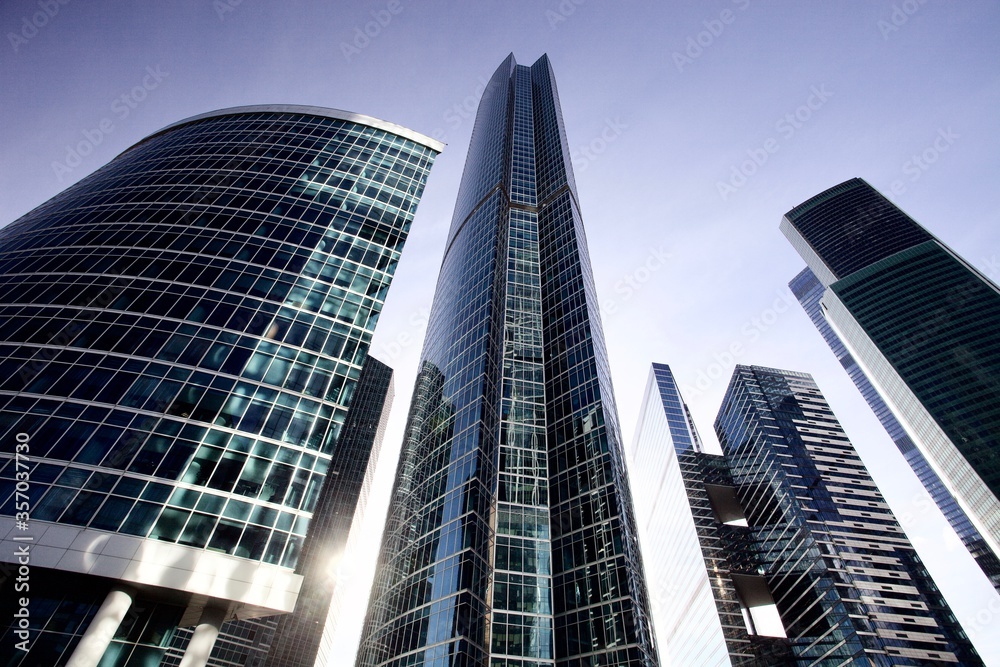 Naklejka premium Office and residential skyscrapers on bright sun and clear blue sky background. Commercial real estate. Modern business city district. Office buildings exterior. Financial city district. Downtown.