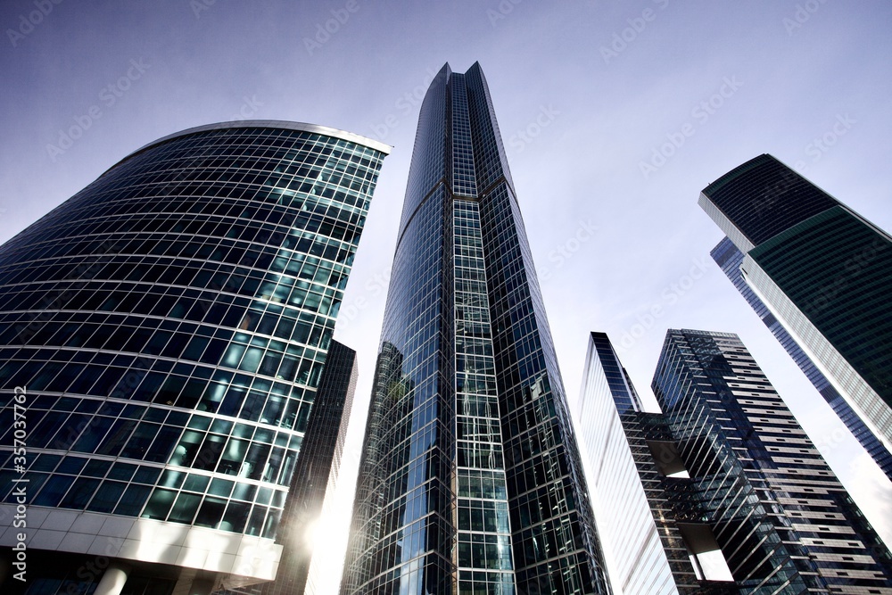 Obraz premium Office and residential skyscrapers on bright sun and clear blue sky background. Commercial real estate investment. Modern business city district. Office buildings. Financial city area. Downtown.