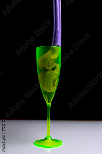 Glass with colored slime with decorations over black background. Children fun and leisure activities. 