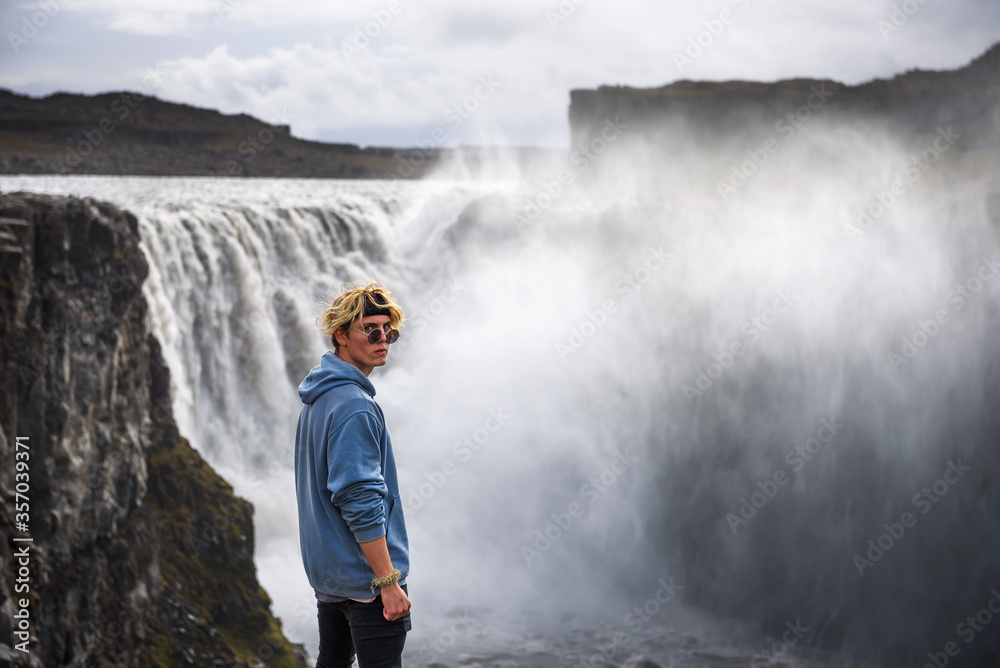 Hiker standing at the edge of the Dettifoss waterfall in Iceland Hiker standing at the edge of the Dettifoss waterfall in Iceland