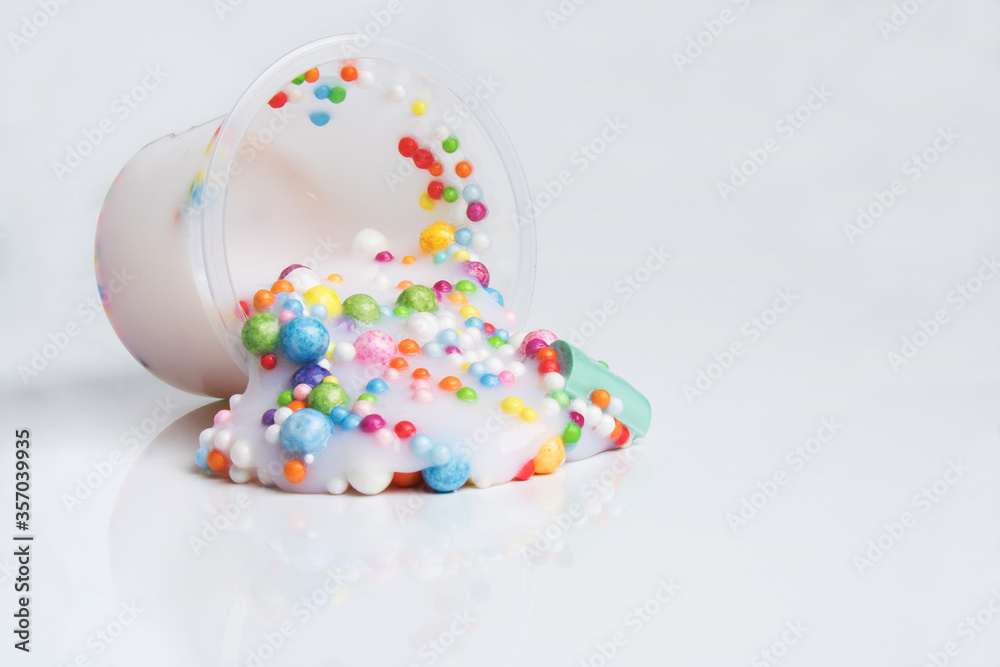 Fotografie Boxes of colored slime with decorations over light background