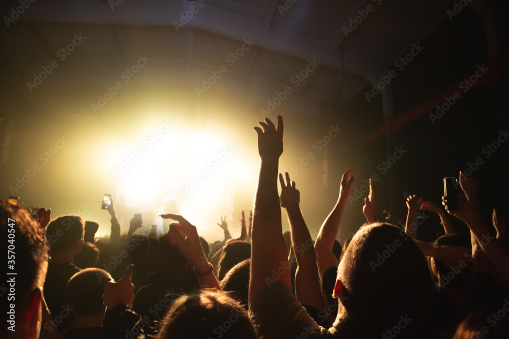 hands of a dancing crowd at a rock concert of a cool band. silhouette of a musician on stage in a haze. music festival banner