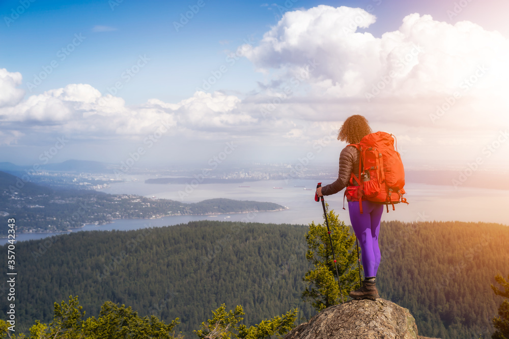 Naklejka premium Adventurous Girl hiking with a backpack on top of a mountain with a beautiful Canadian Nature Background. Taken in Bowen Island, near Vancouver, British Columbia, Canada.