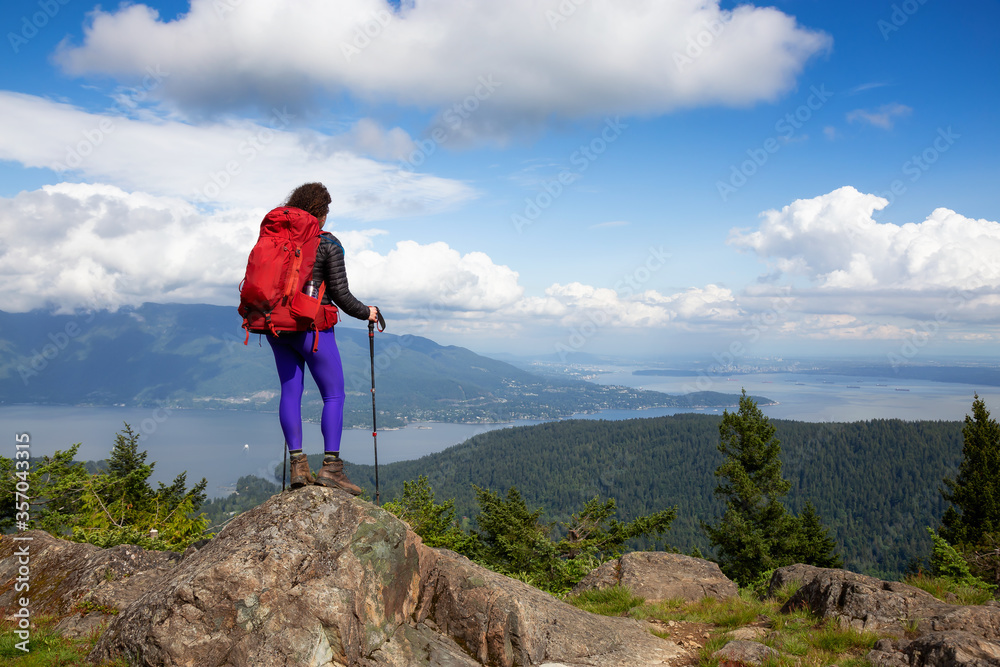 Adventurous Girl hiking with a backpack on top of a mountain with a beautiful Canadian Nature Background. Taken in Bowen Island, near Vancouver, British Columbia, Canada.