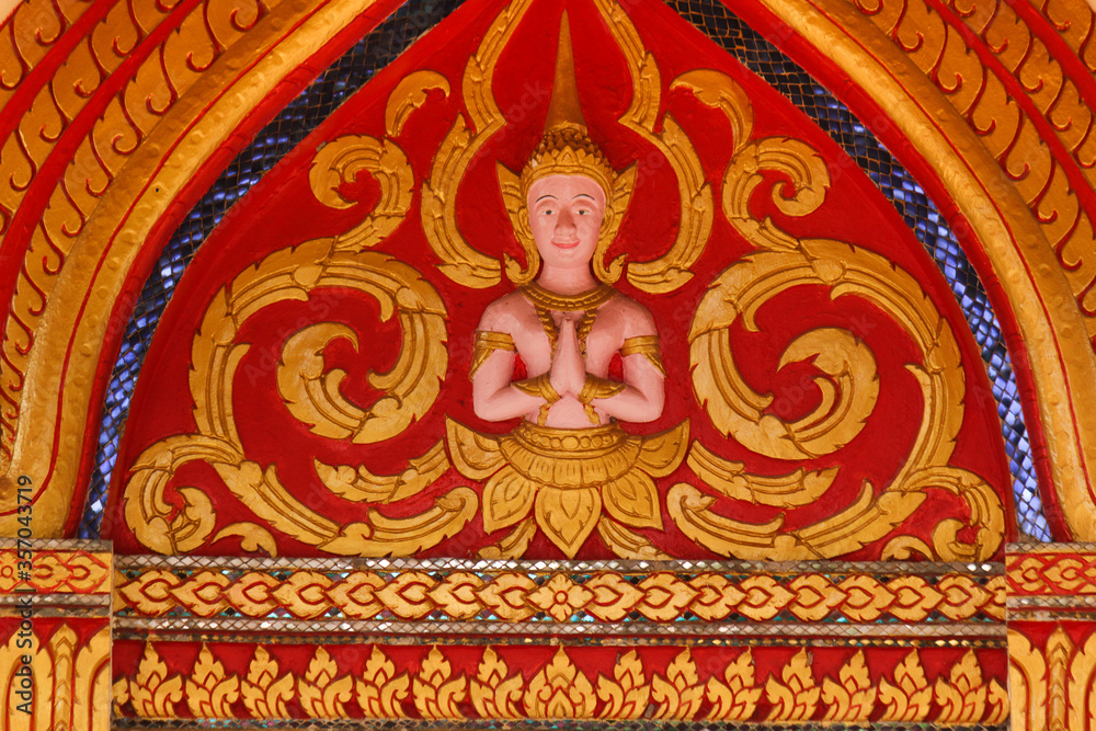 Buddha image fresco on a red and golden painted wall of a wat in Siamese Lao PDR, Southeast Asia