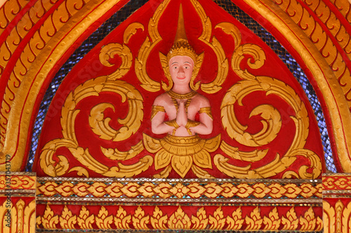 Buddha image fresco on a red and golden painted wall of a wat in Siamese Lao PDR, Southeast Asia © Carolin