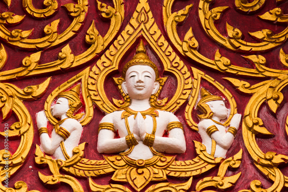 Golden buddha image frescoes on a red wall of a wat in Siamese Lao PDR, Southeast Asia