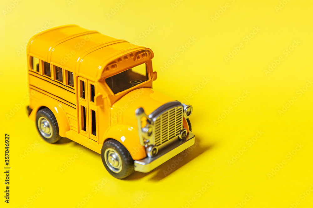Simply design yellow classic toy car school bus isolated on yellow colorful background. Safety daily transport for kids. Back to school concept. Education symbol, copy space