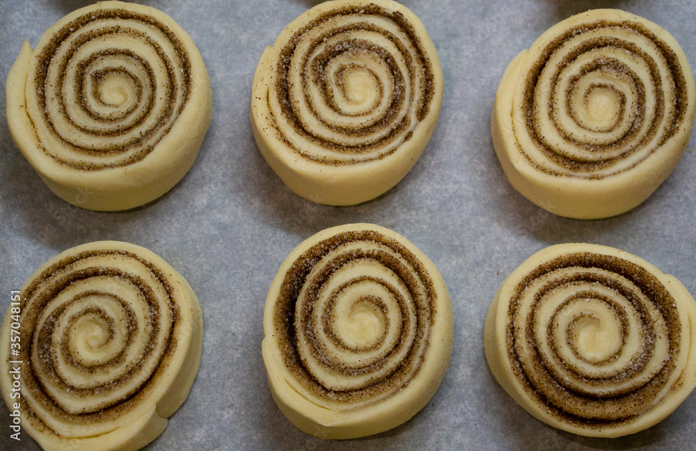 Classic buns with cinnamon and sugar. Cinnabon dough ready for baking. Cinnamon rolls shot with selective focus. Tasty pastry concept.